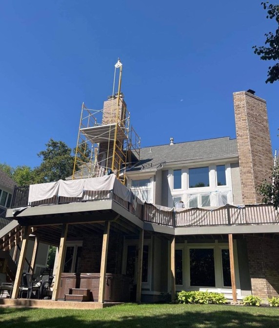 Technician performing a detailed chimney inspection on a brick chimney in Leawood, KS.