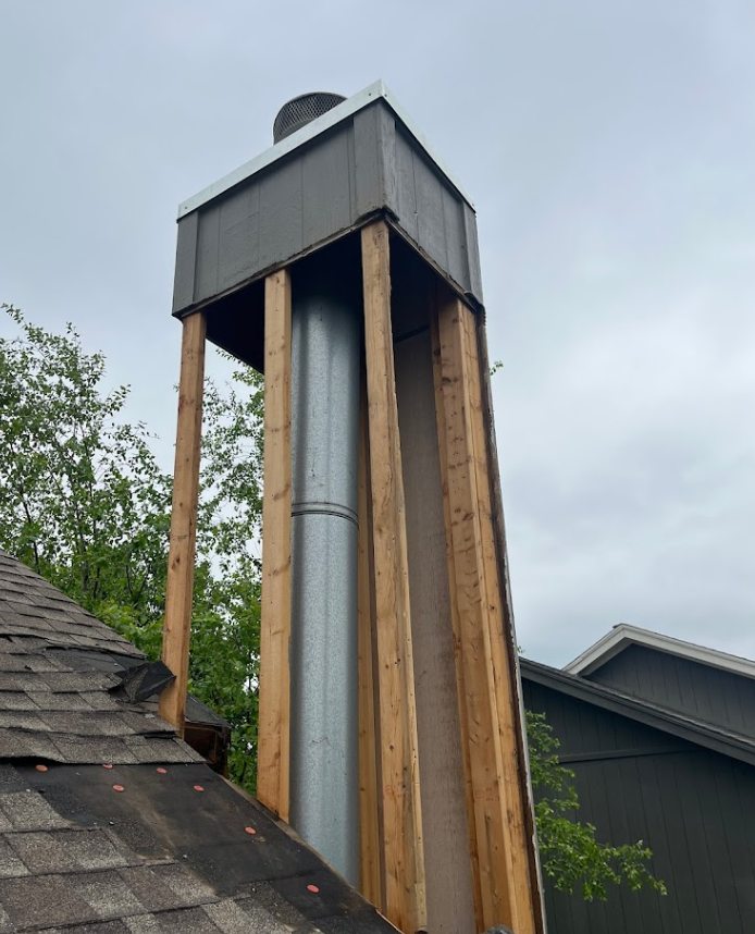 Professional chimney sweep carefully cleaning a brick chimney at a home in Lee’s Summit, MO.