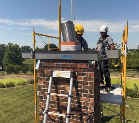 Chimney technician using advanced tools to remove creosote buildup from a residential chimney in Lee’s Summit, MO.