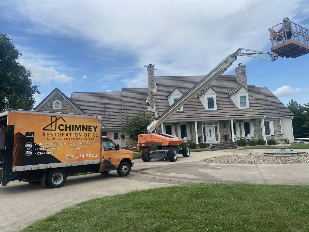 Chimney Repair on Kansas City Home with Branded Work Trucks and crew on lift repairing chimney exterior