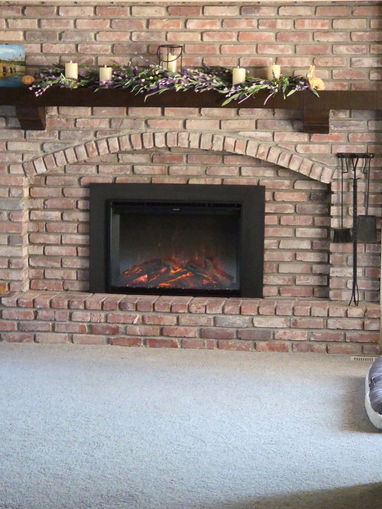 Brick arched fireplace with new insert professionally installed by Chimney Restoration of Kansas City during chimney restoration project