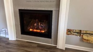 A modern fireplace glows within a framed, unfinished surround; nearby wall reveals insulation and piping