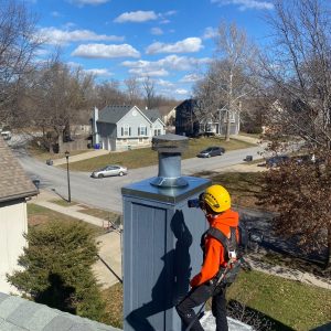 Chimney Restoration of KC teammate on roof installing new chase cover and spark arrestor chimney cap in Overland Park KS